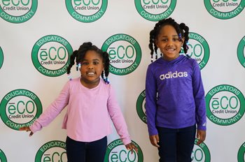 Two kids pose in front of the eCO Step N Repeat